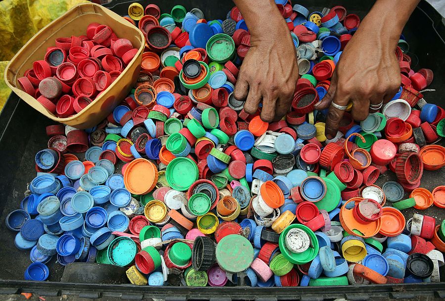 Mensch sortiert Schraubverschlüsse aus Plastik 
