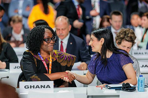 German Federal minister Reem Alabali Radovan at the UN conference in Sevilla shaking hands with the women representing Ghana and sitting next to her