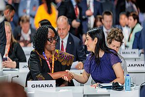 Bundeswntwicklungsministerin Reem Alabali Radovan schüttelt auf der UN-Konferenz in Sevilla der neben ihr sitzenden Vertreterin aus Ghana die Hand