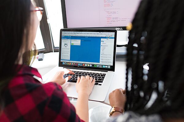 Frauen vor Computerbildschirmen am Schreibtisch
