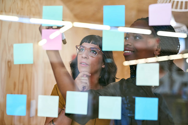 Person hinter einer Scheibe, auf der Post-its kleben/ Person behinds window with Post-its