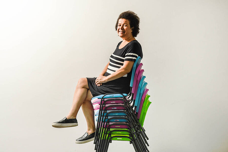 Frau sitzt auf gestapelten Stühlen 