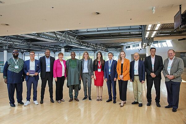 Eine Gruppe von zw&ouml;lf Menschen posiert in einer Halle f&uuml;r ein Foto.